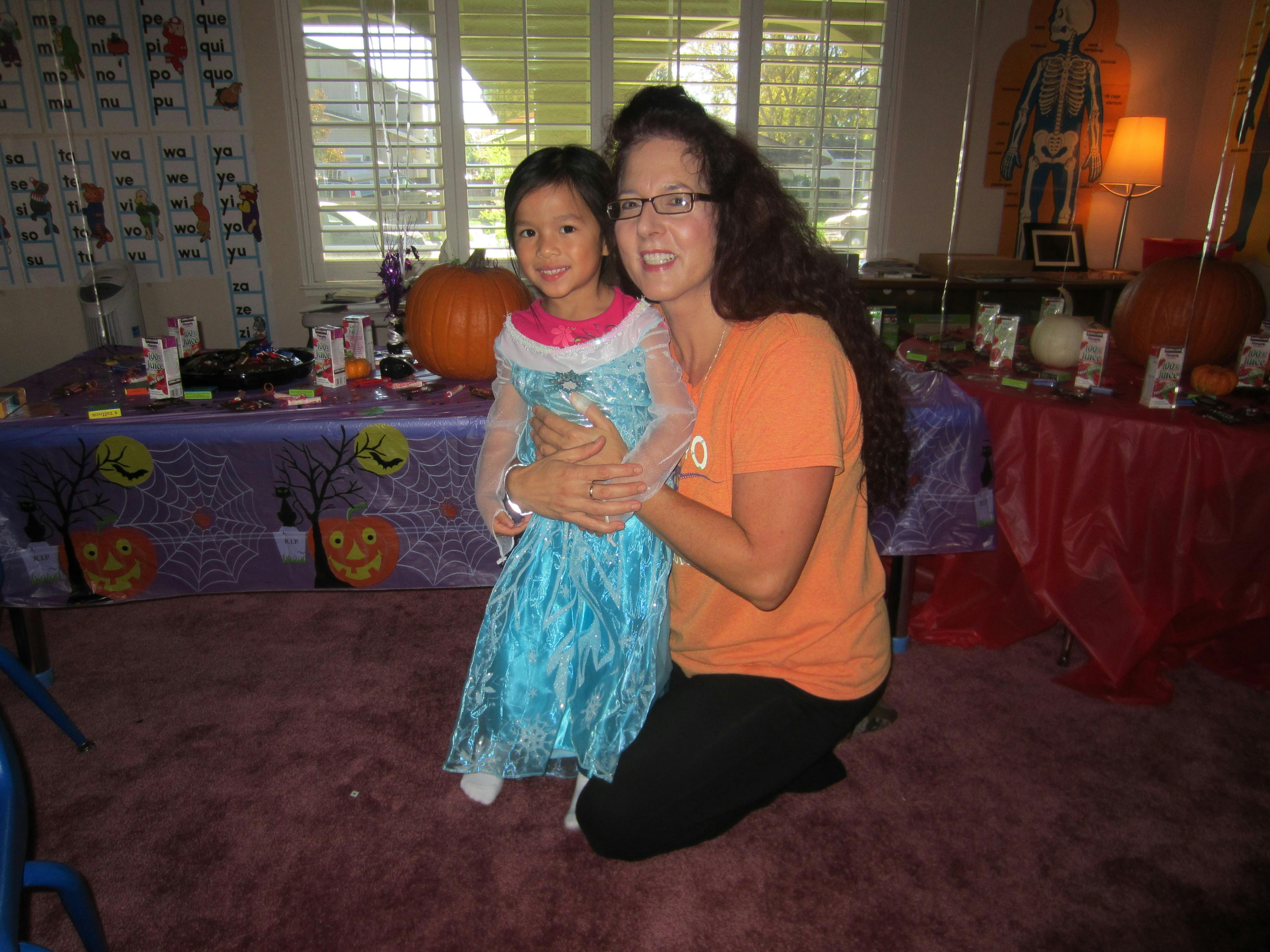 Person kneeling and holding a child in a blue dress