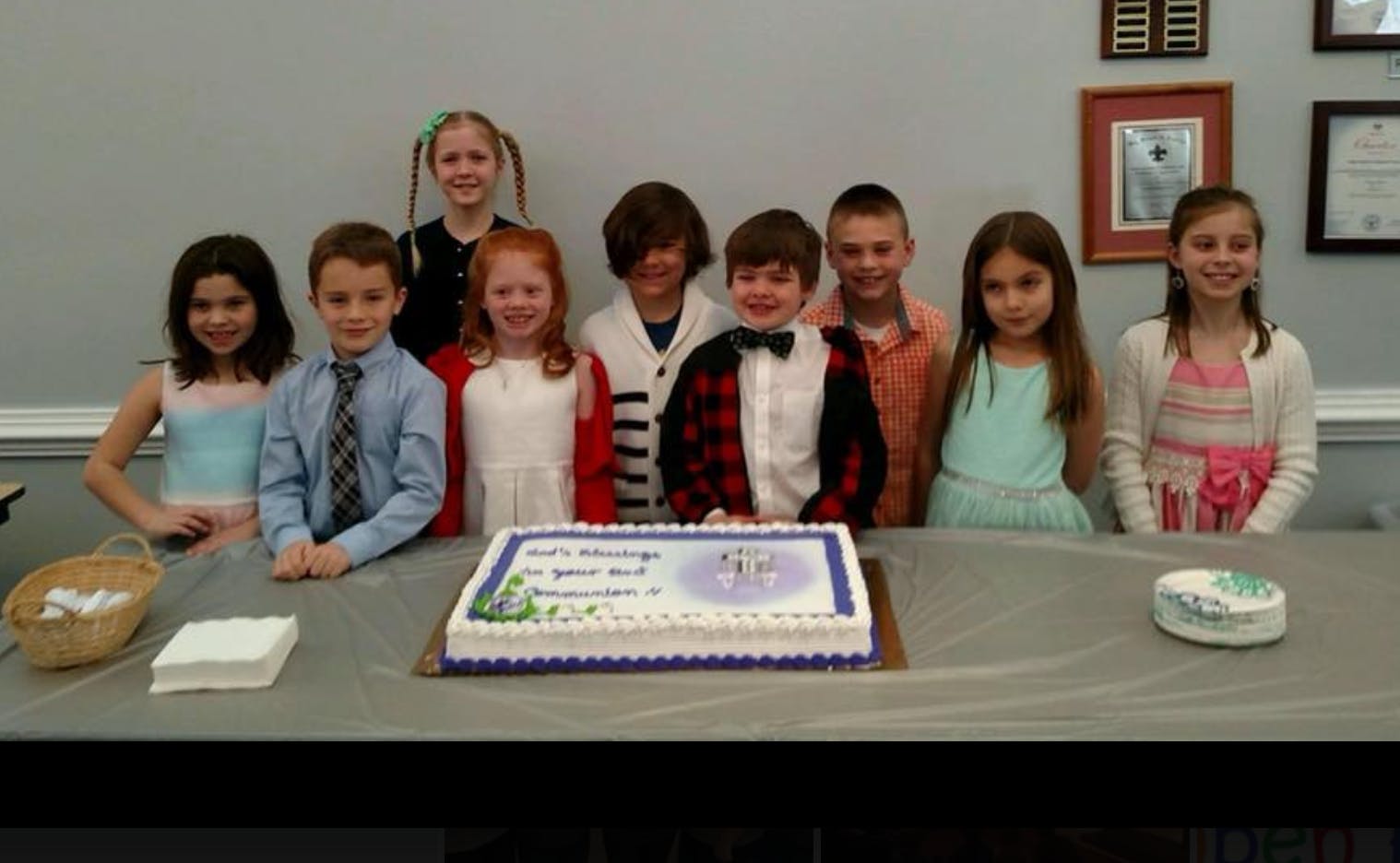 Group of children standing behind a table with a cake