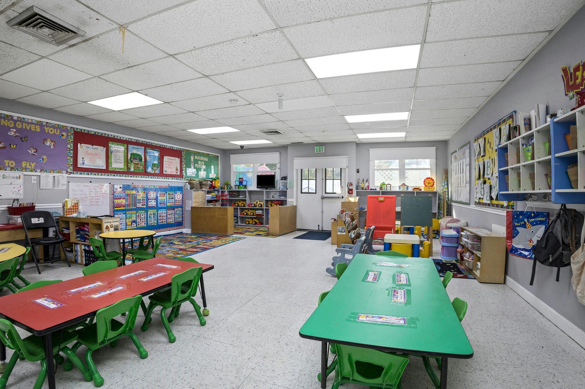 Classroom with small tables and chairs, bulletin boards with educational posters