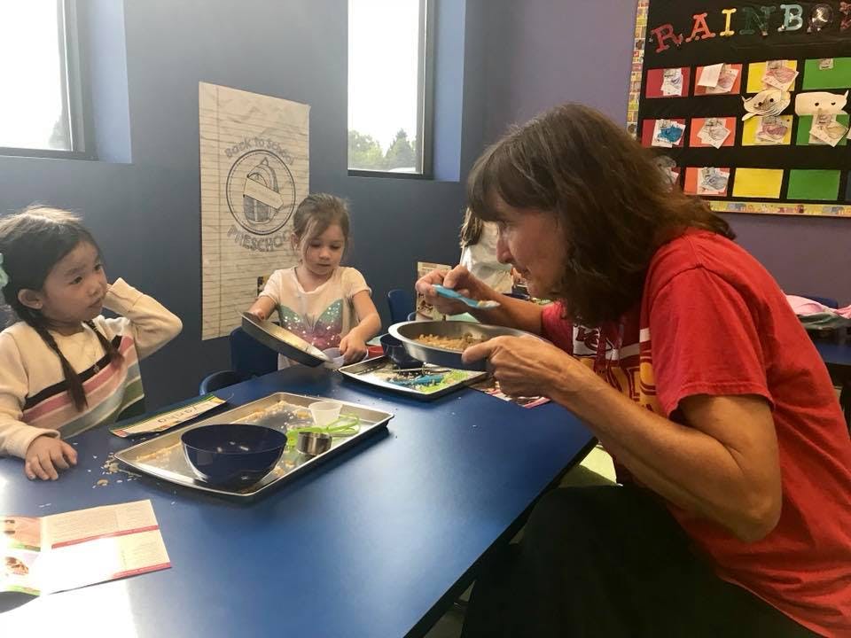 Adult and two children at a table with bowls and trays