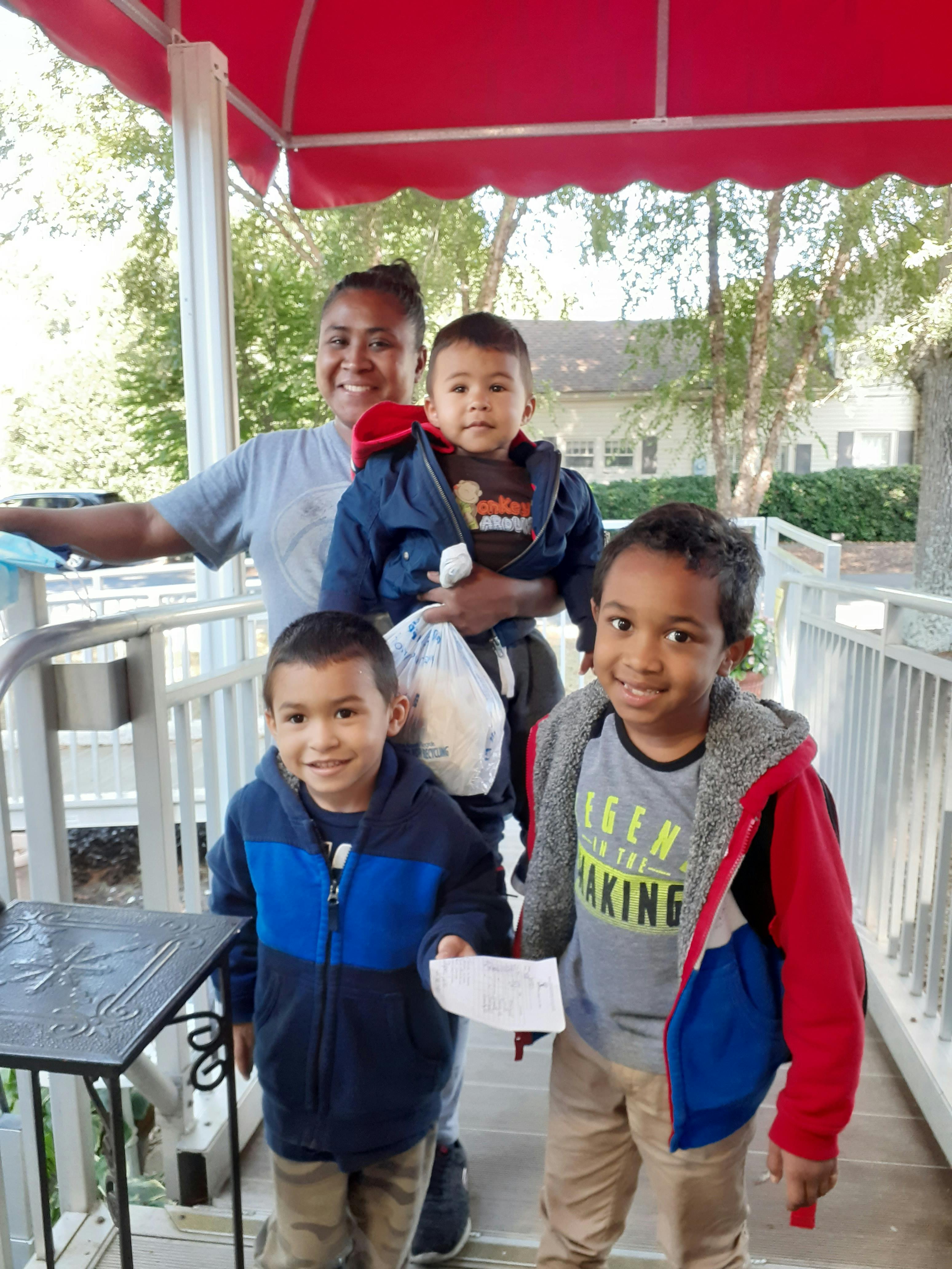 Person holding a child, with two other children standing nearby