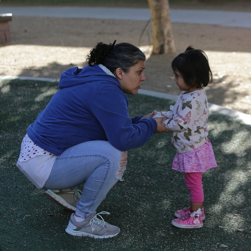 Person crouching and holding hands with a child