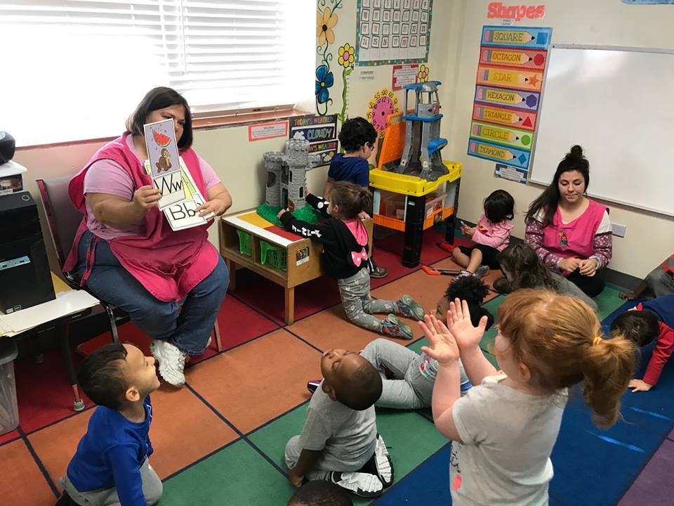 Person reading a book to children in a classroom