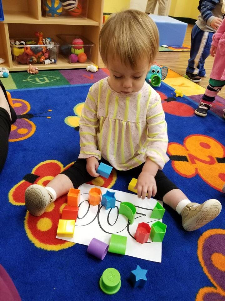Child sitting on a rug playing with colorful blocks and shapes