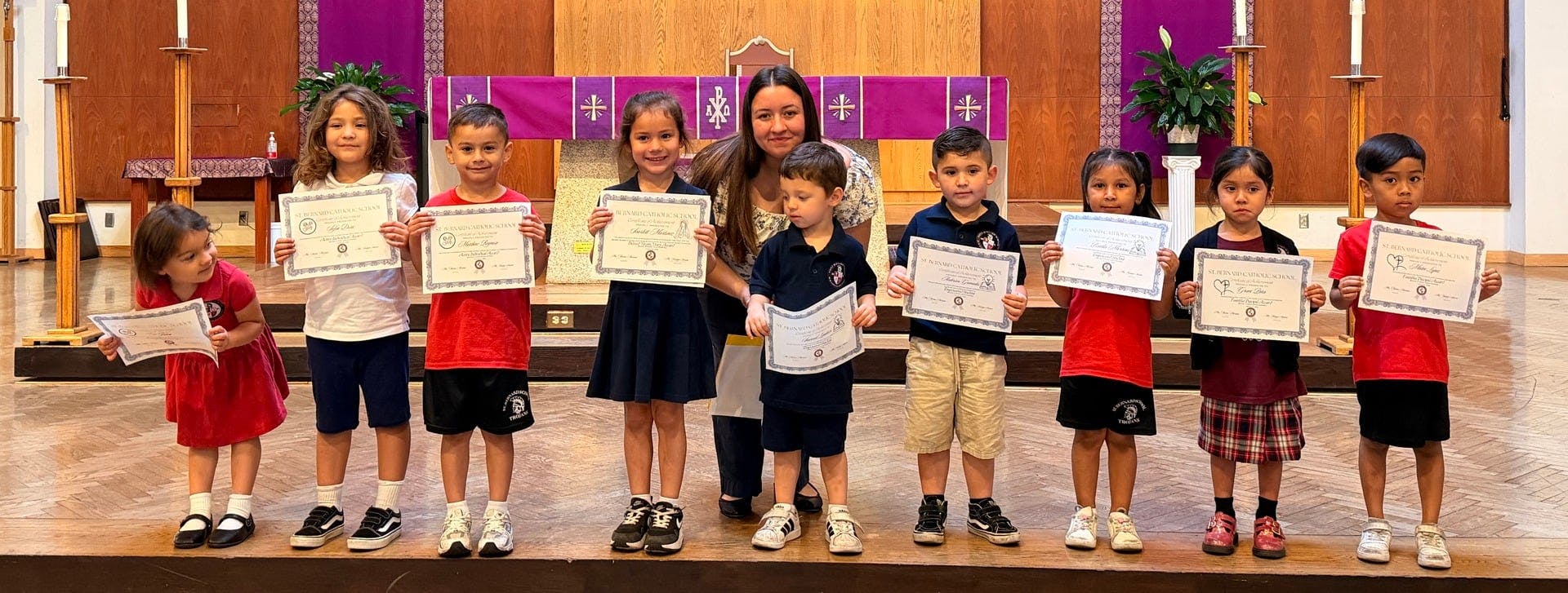 Adult and group of children holding certificates on a stage