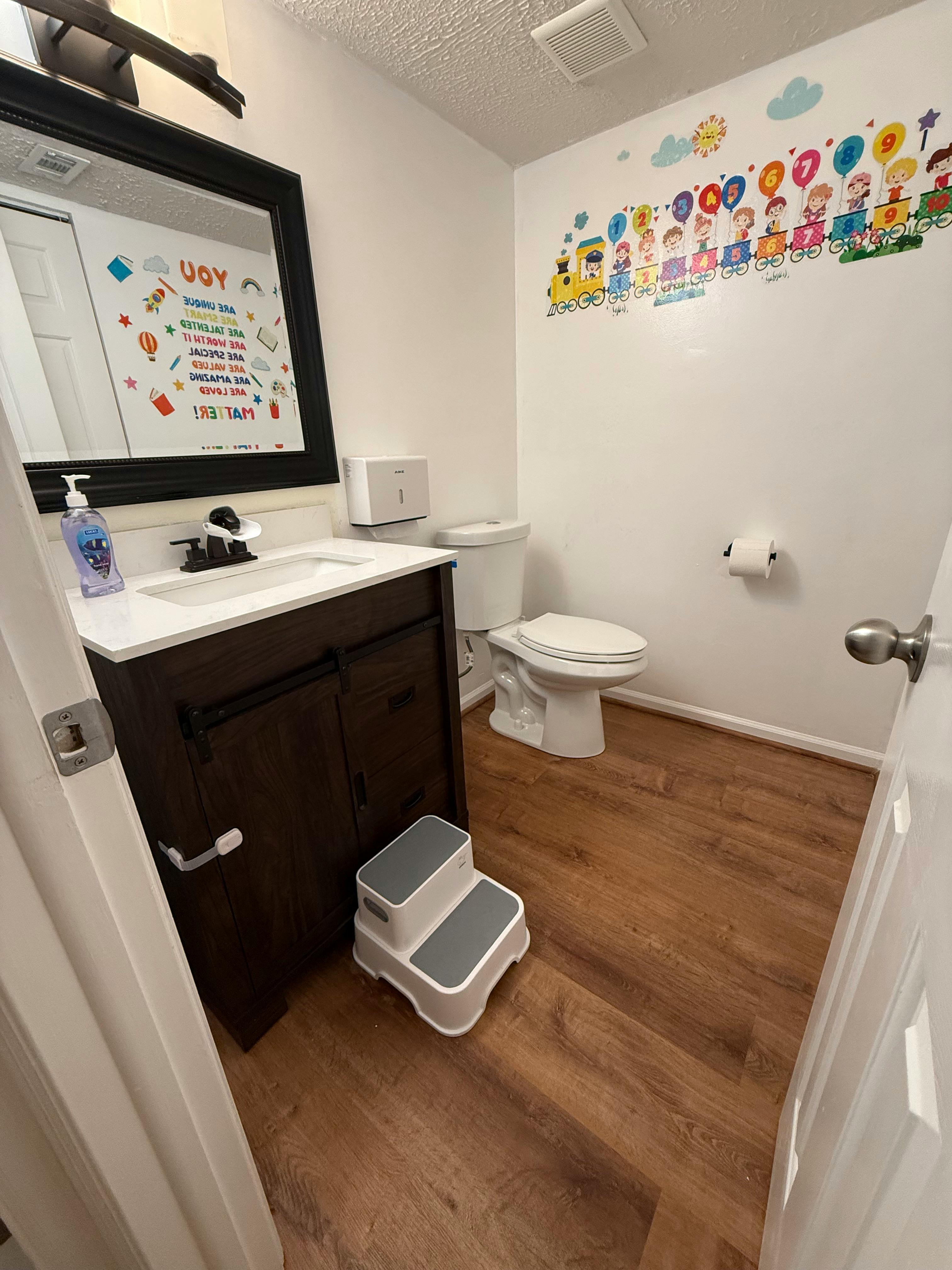 Child-friendly bathroom with a step stool, toilet, and decorative wall decals