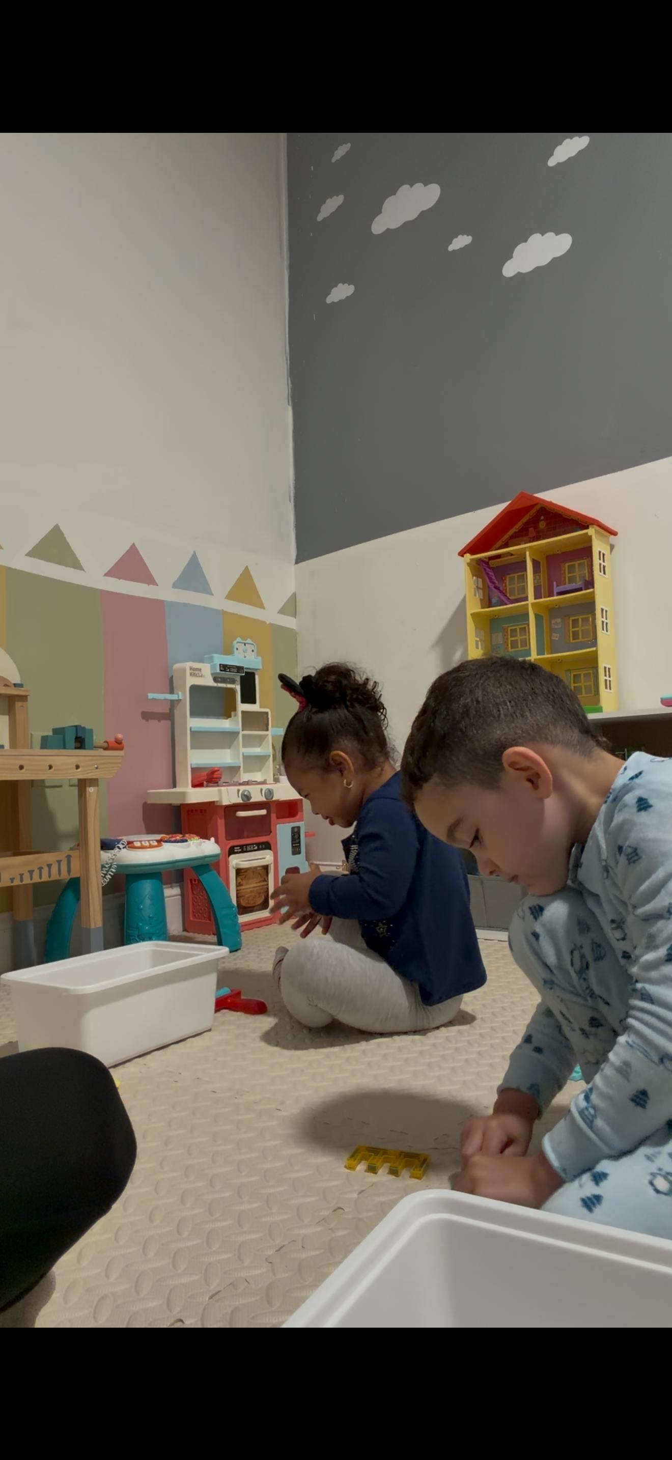 Two children playing with toys on a playroom floor
