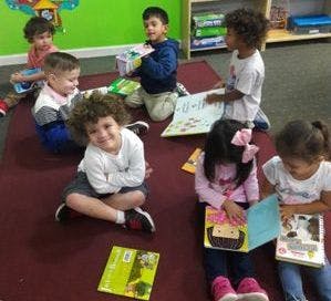 Children sitting on a rug reading books