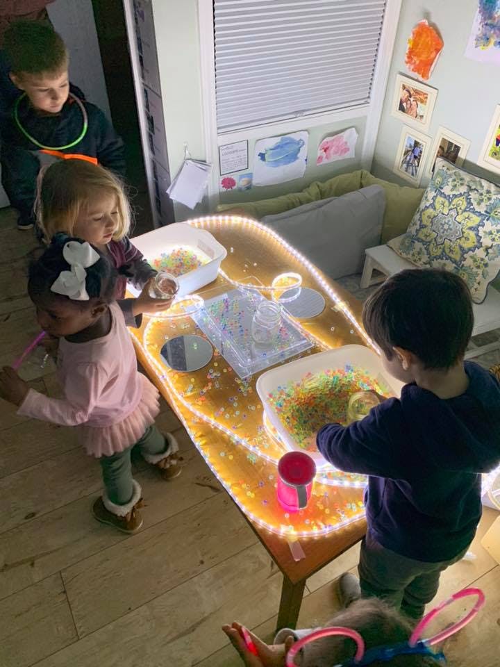 Children playing at a light table with sensory bins