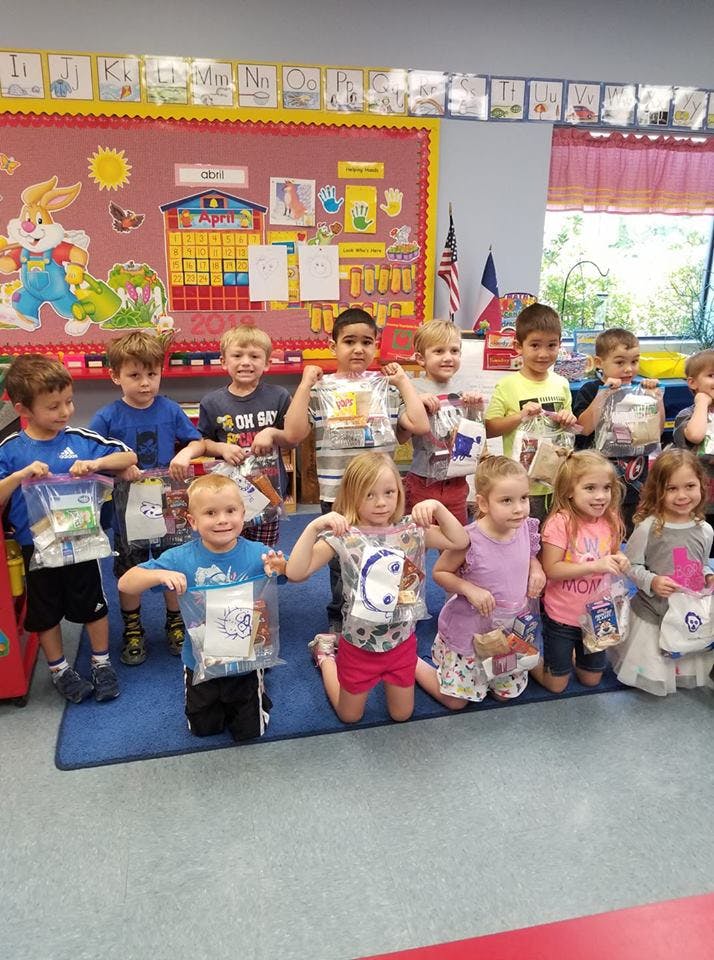 Group of children holding up clear bags in a classroom