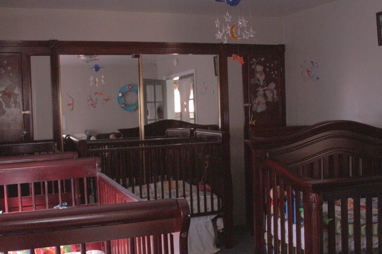 Multiple wooden cribs in a room with a large mirror