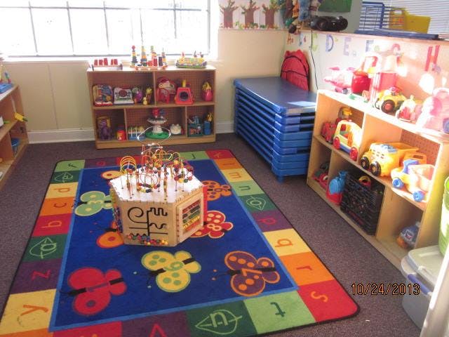 Playroom with a colorful rug, toy shelves, and blue mats