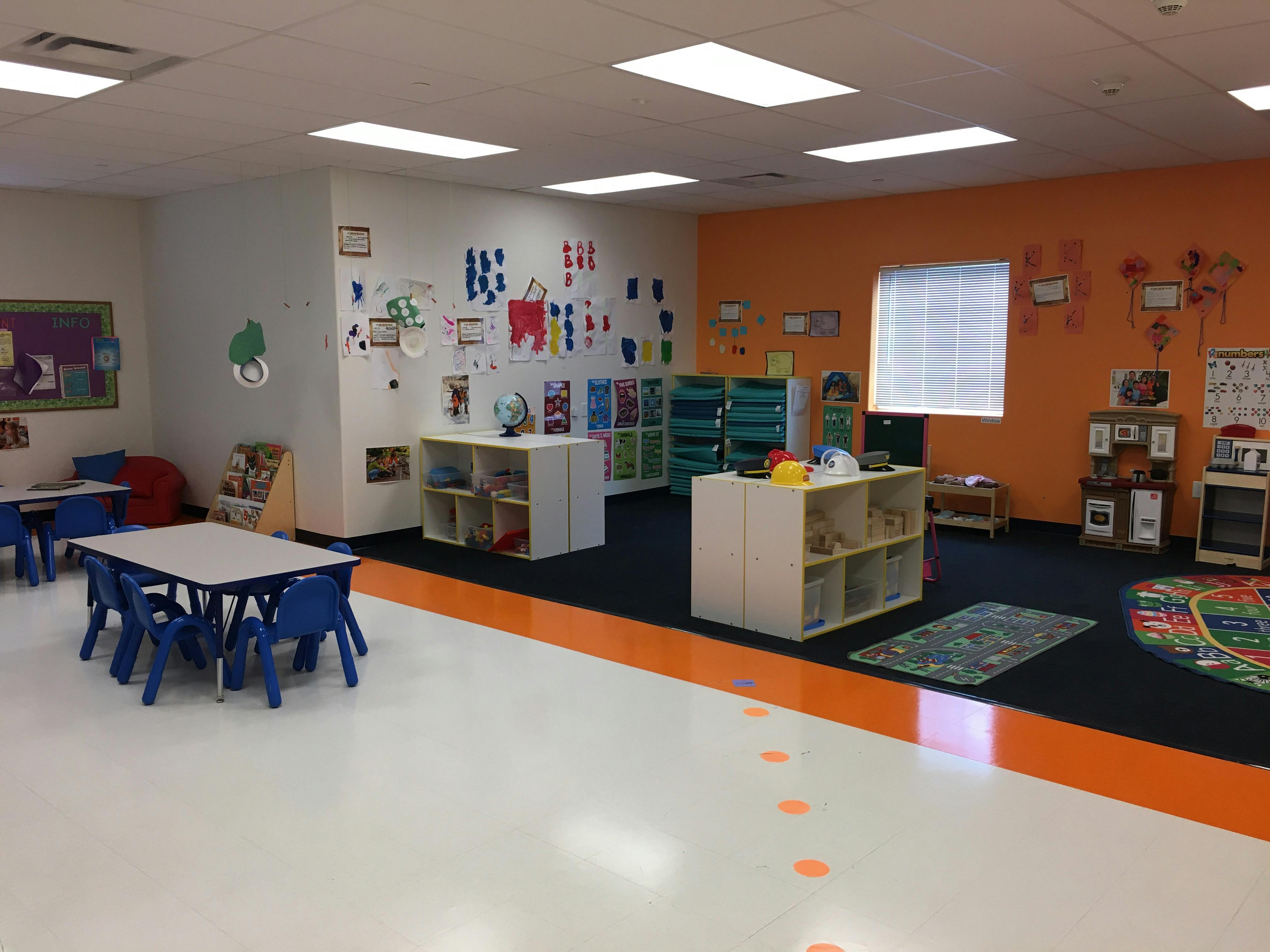 Classroom with small tables and chairs, shelves, and artwork on walls