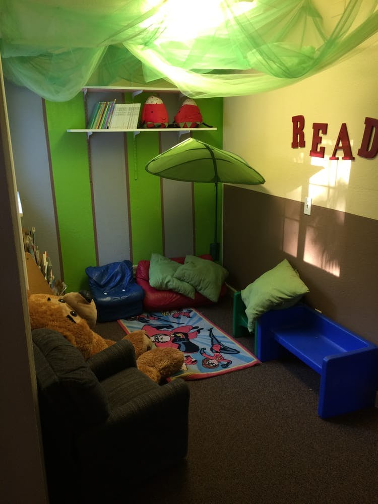 Children's reading nook with beanbags, small couch, and "READ" letters on wall