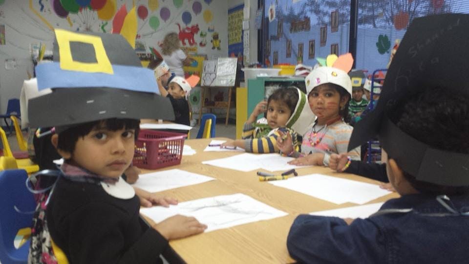 Children wearing hats sitting at a table in a classroom