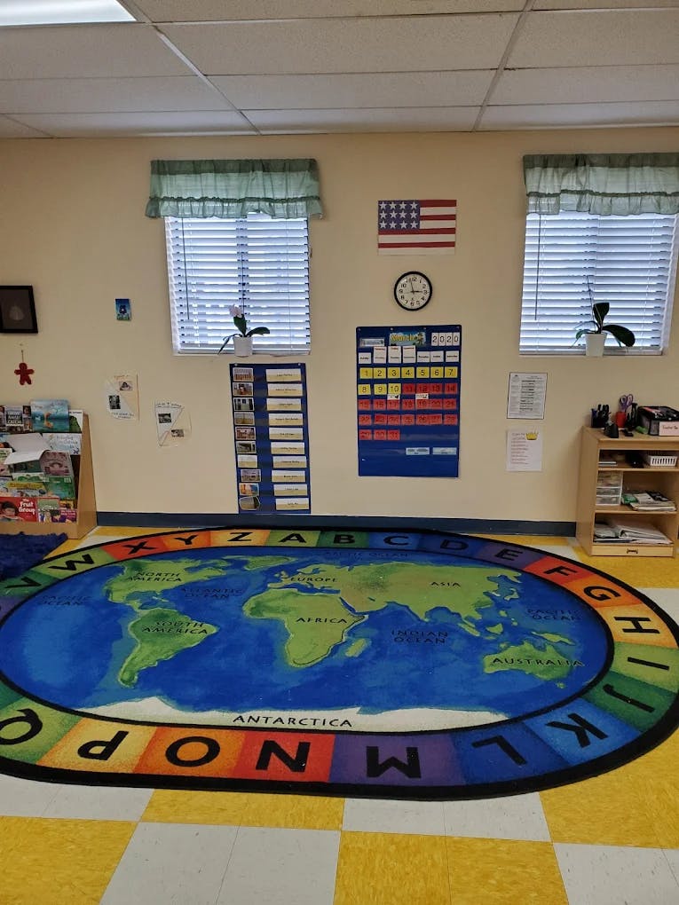 Classroom with a world map rug and calendar on the wall