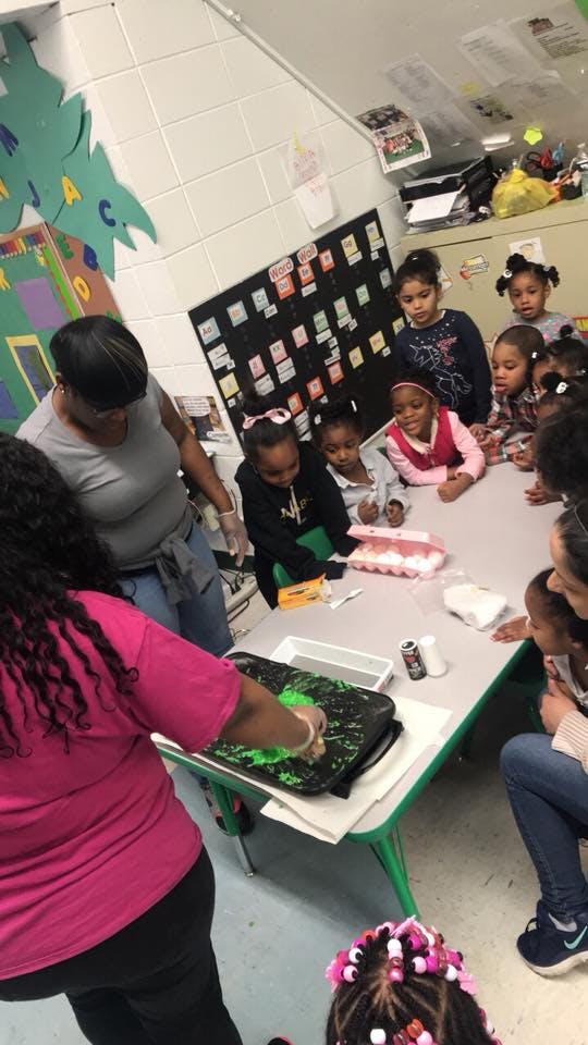 Adults and children gathered around a table in a classroom