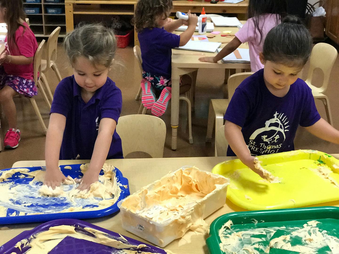 Two children playing with sensory bins at a table