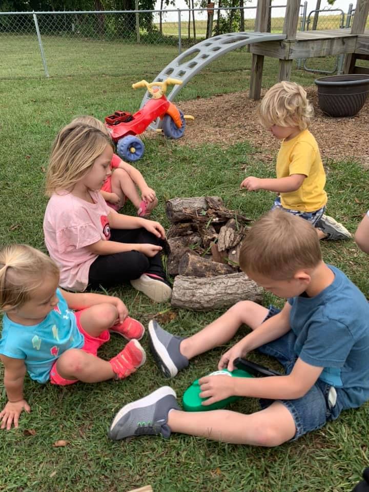 Children playing on grass with logs and toys