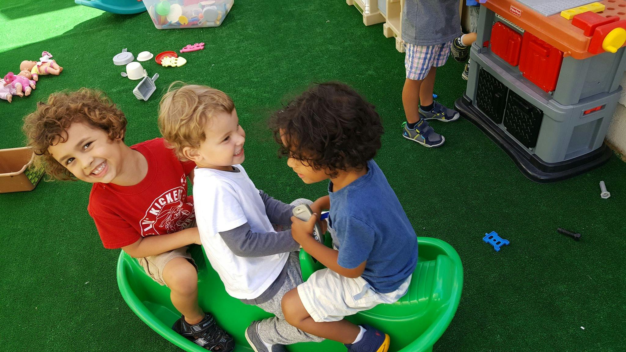 Three children playing on a green seesaw