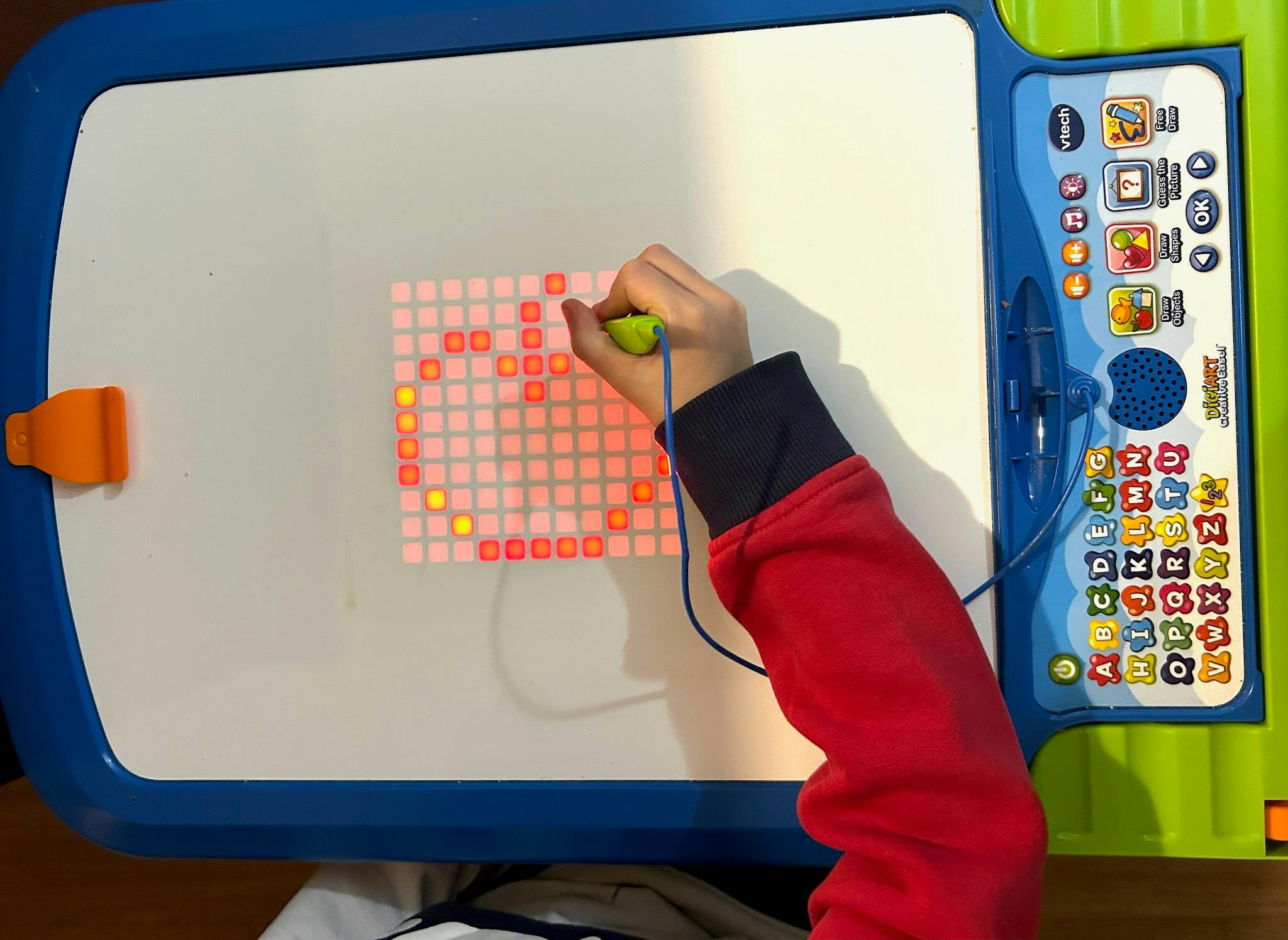 Child drawing on a light-up pegboard with a stylus