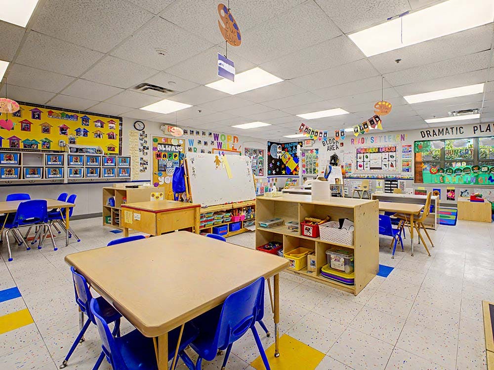 Classroom with small tables and chairs, and learning materials on shelves and walls