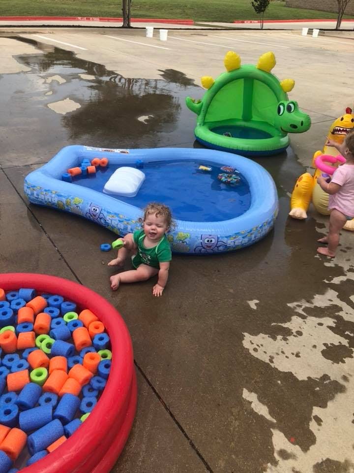 Child sitting next to an inflatable pool with another child standing nearby