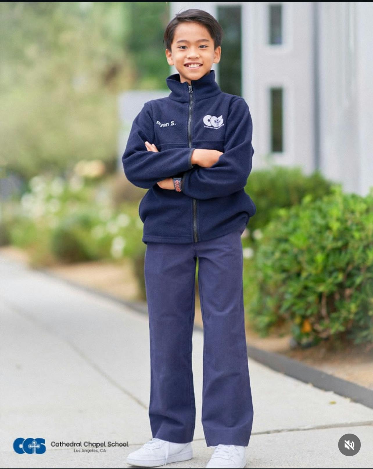 Child in a navy blue uniform jacket and pants with arms crossed