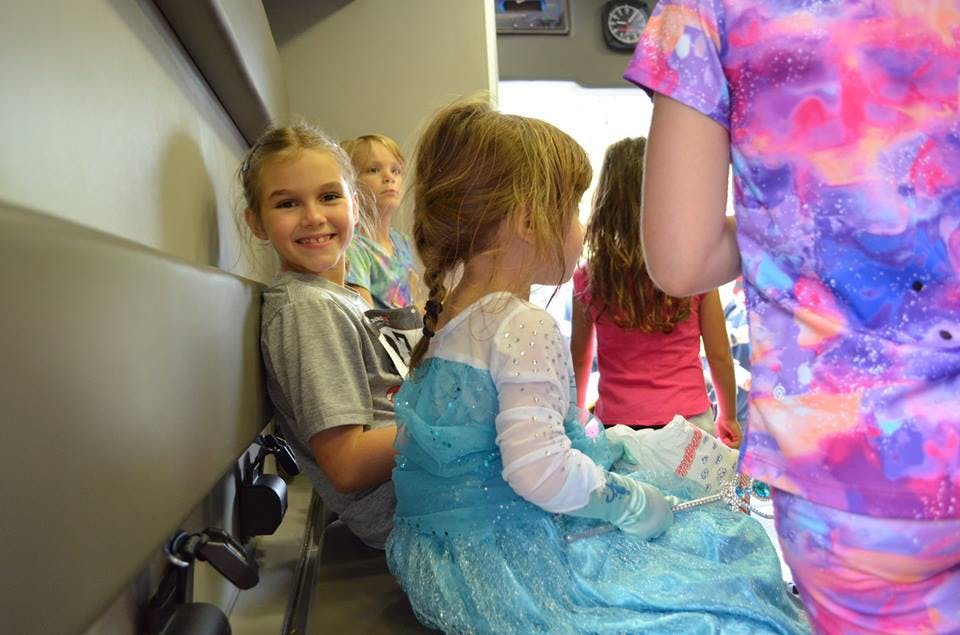 Child in blue dress sitting with other children