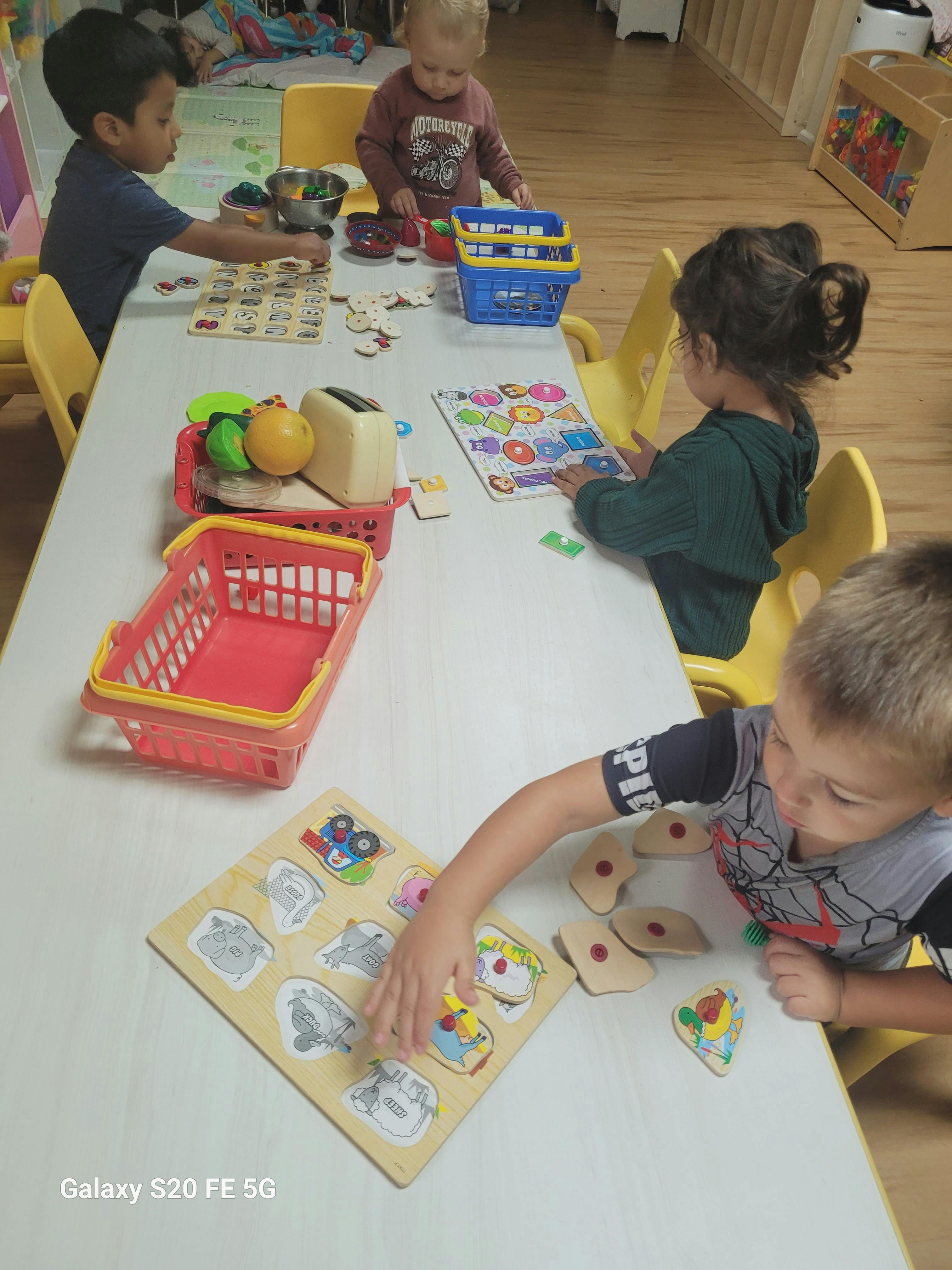 Children playing with puzzles and toys at a table
