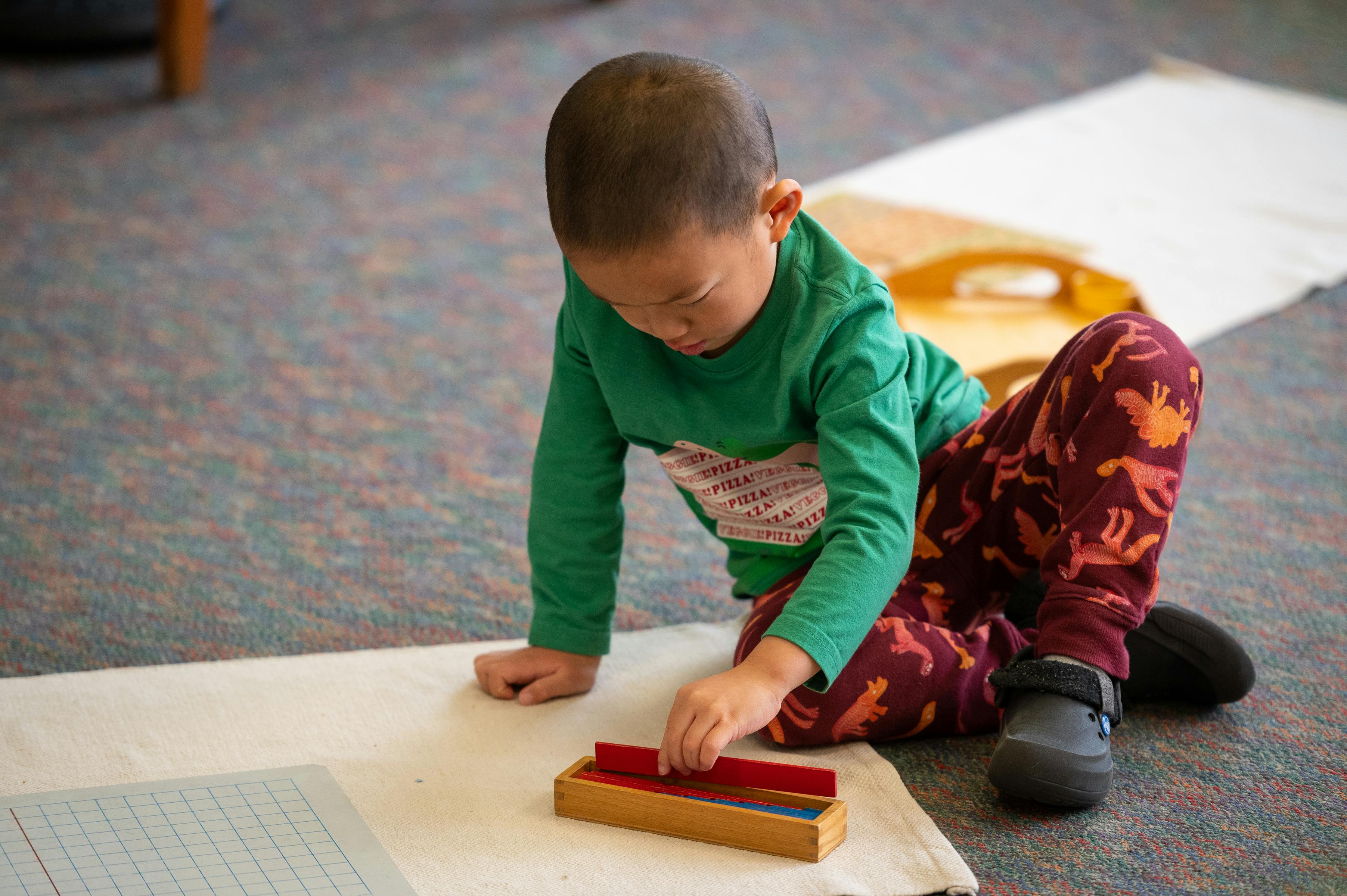 Child playing with a wooden block toy on the floor