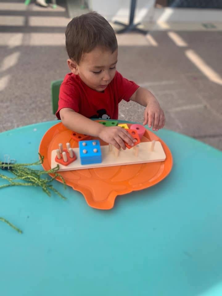 Child playing with a shape sorter toy on a table
