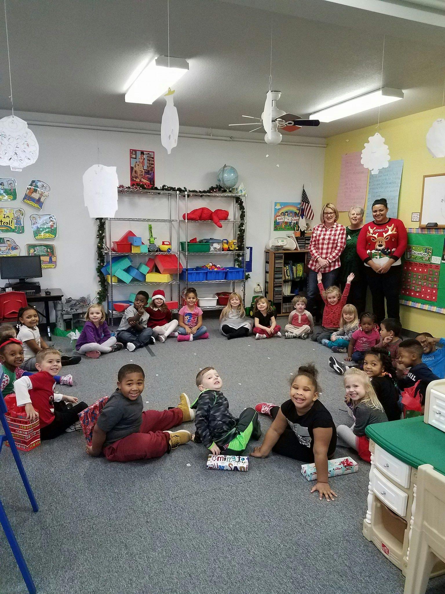 Children and adults sitting on the floor in a classroom