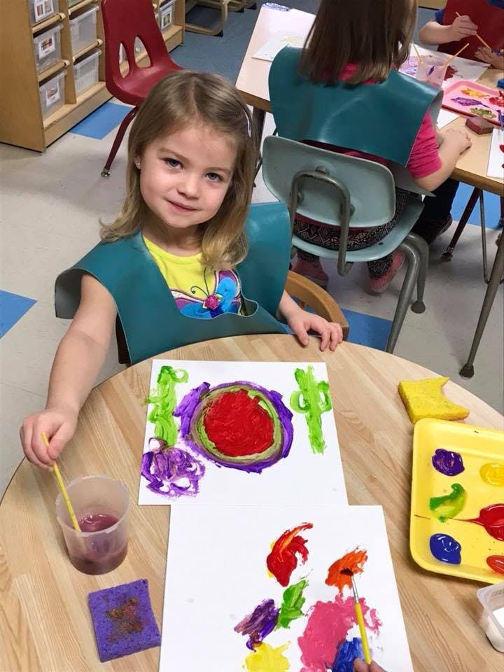 Child painting at a table in a classroom