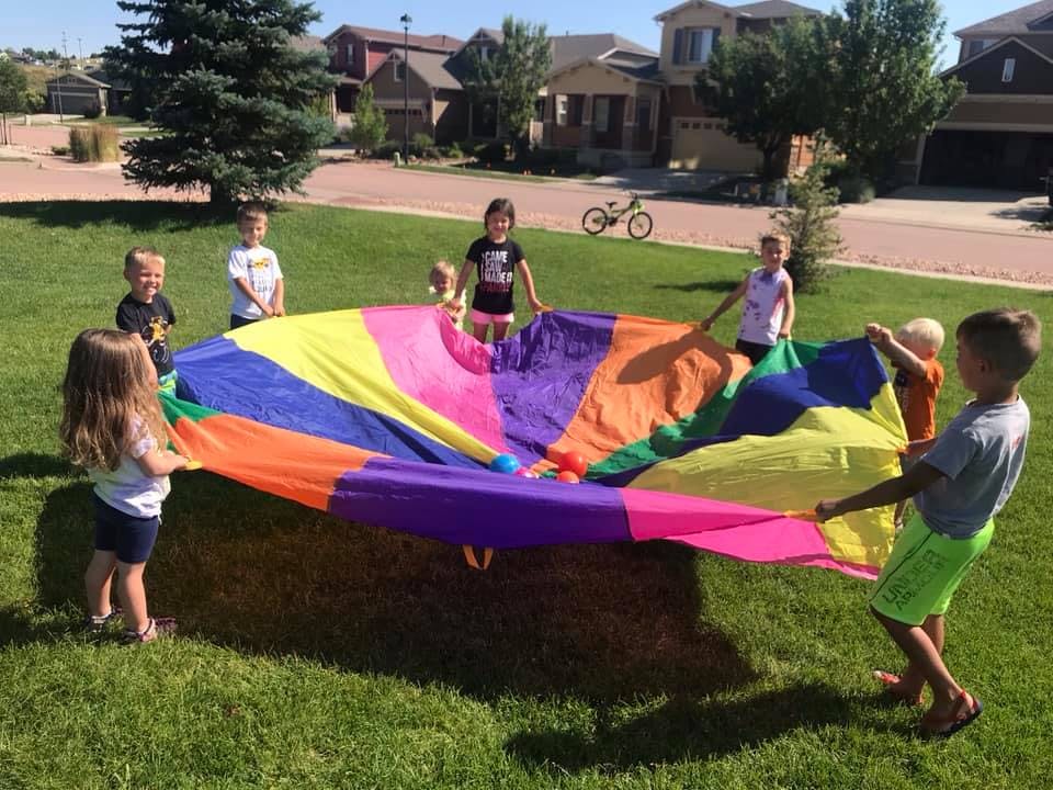 Children playing with a colorful parachute outdoors