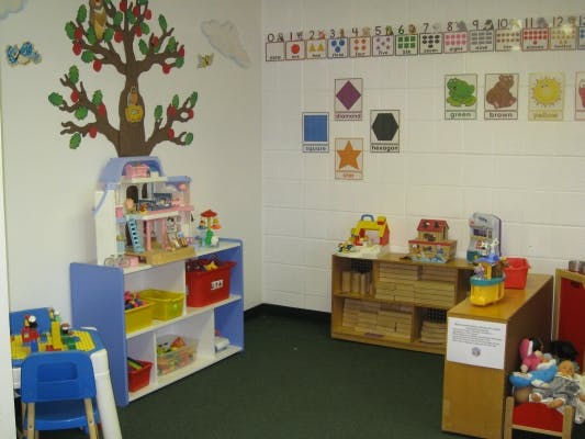 Playroom with shelves of toys, a small table and chairs, and wall decorations