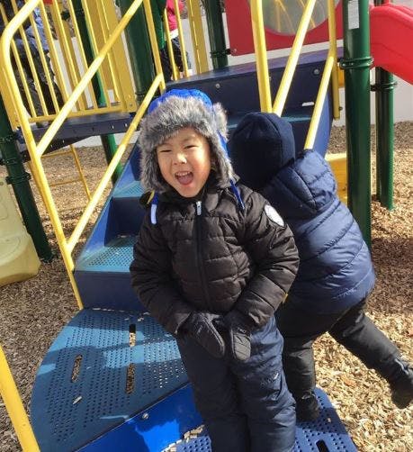 Child in winter clothing on a playground structure