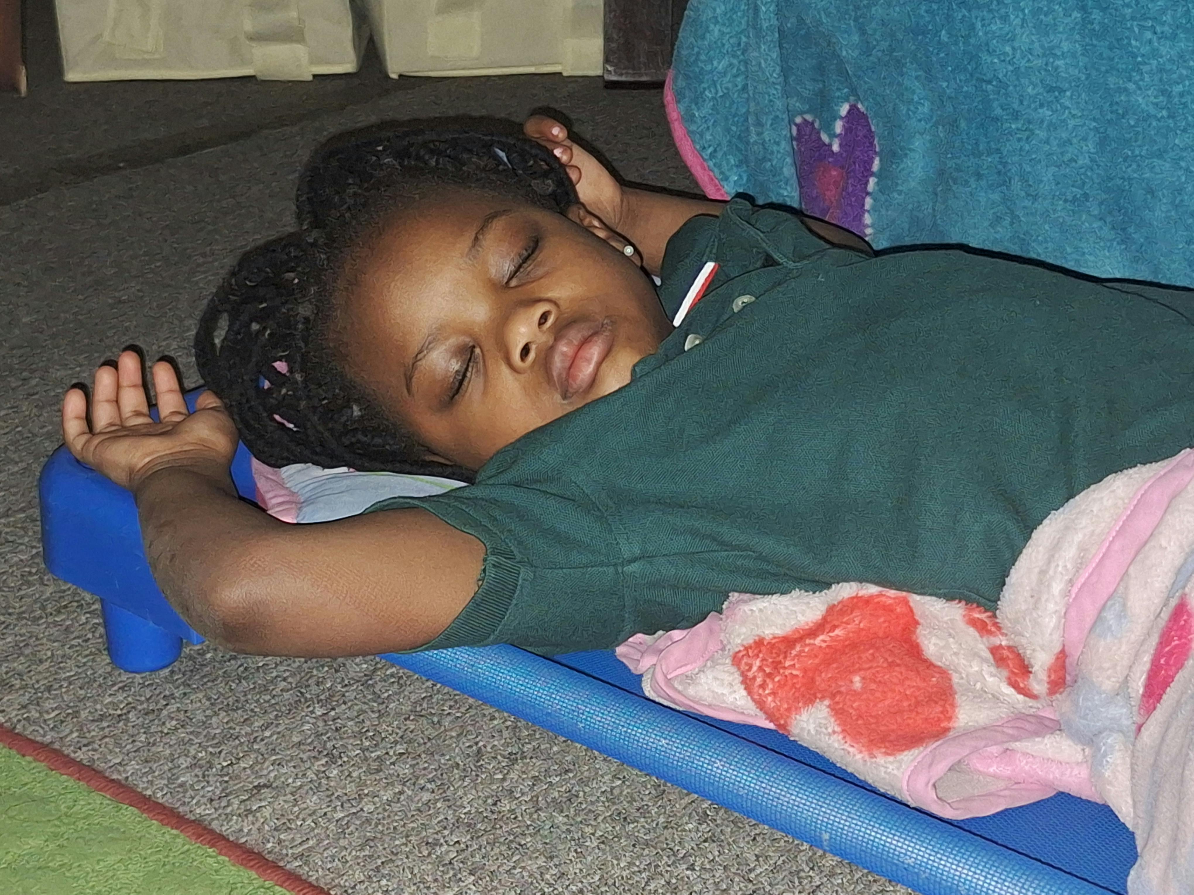 Child sleeping on a blue cot