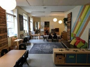 Room with tables, chairs, and a couch with colorful pillows