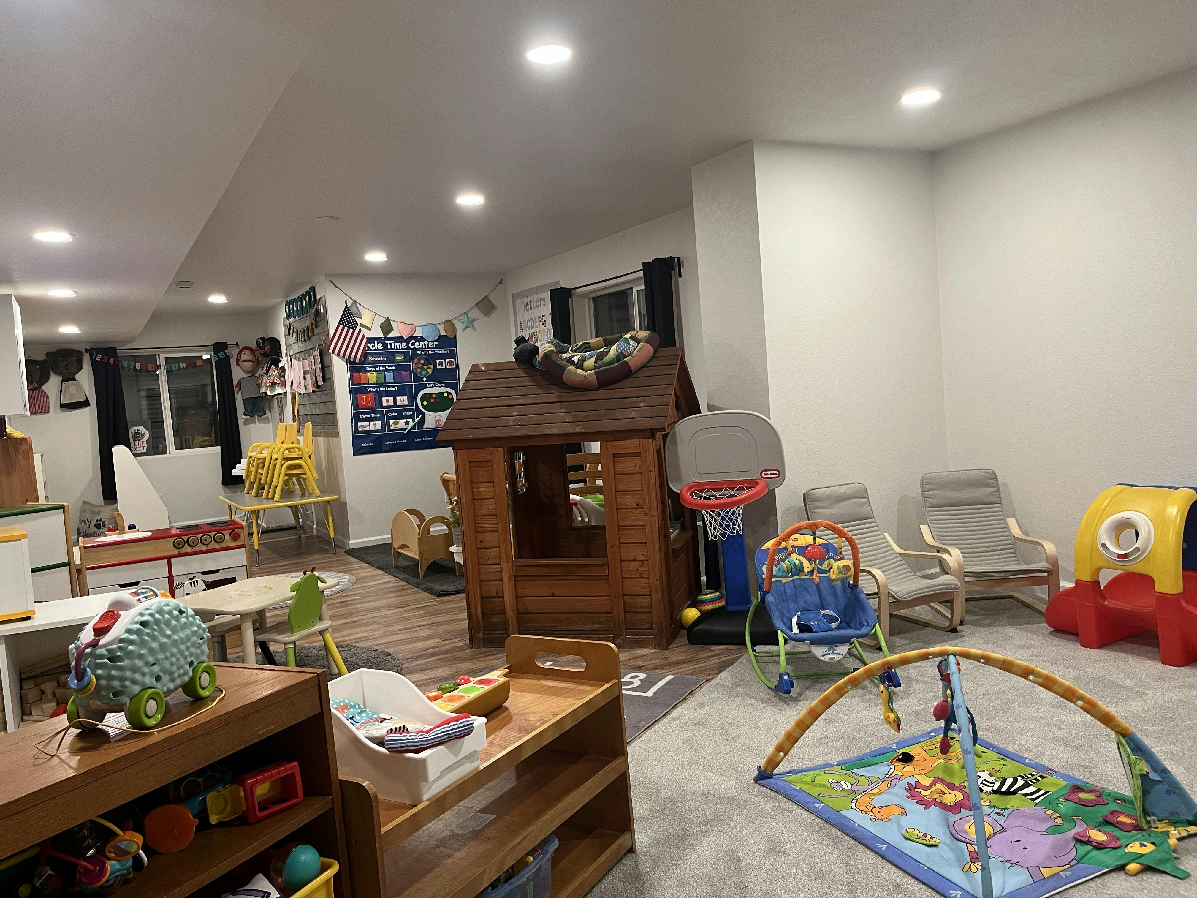 Playroom with a wooden playhouse, toy basketball hoop, and various floor toys