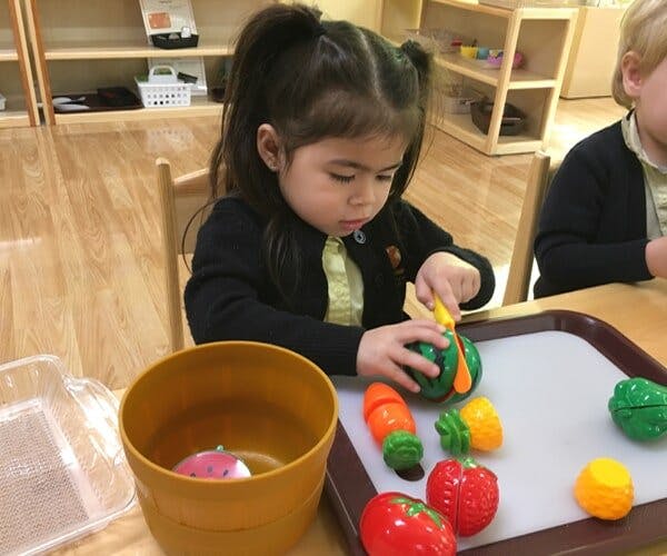 Child playing with toy vegetables and a knife