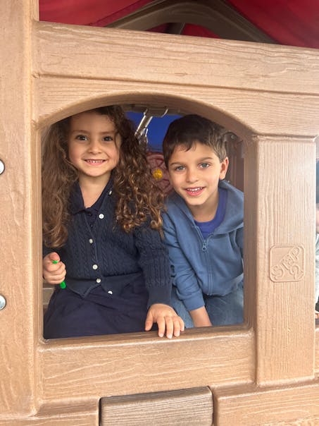 Two children looking out from a playhouse window