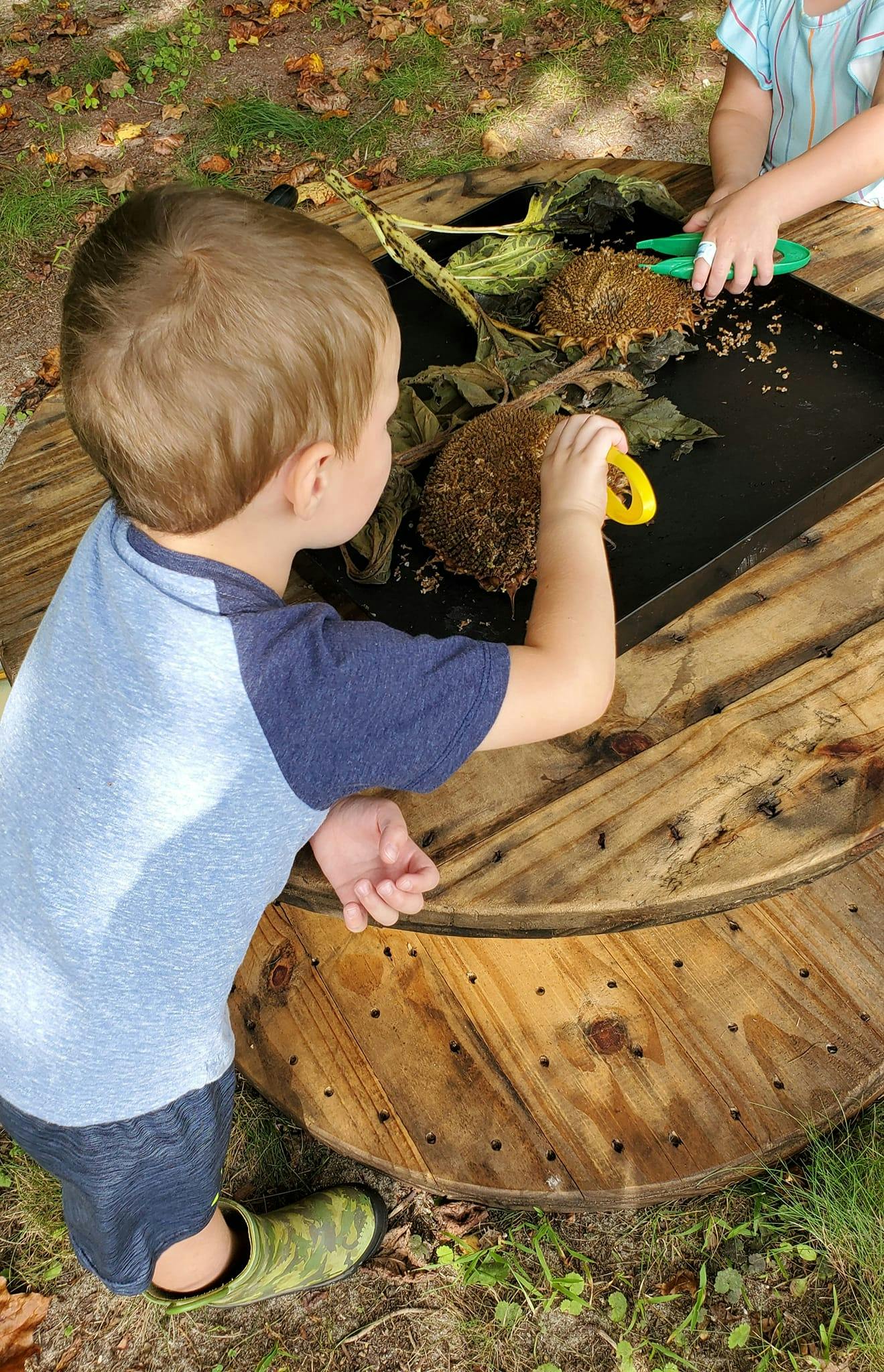 Child playing with natural materials on a wooden spool table