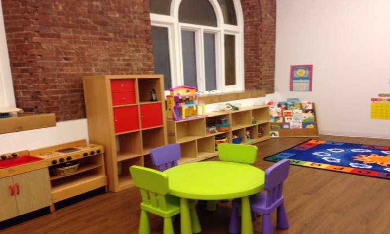 Children's play area with small table and chairs, toy kitchen, and shelves