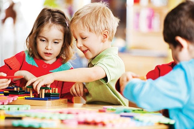 Two children playing with colorful blocks at a table