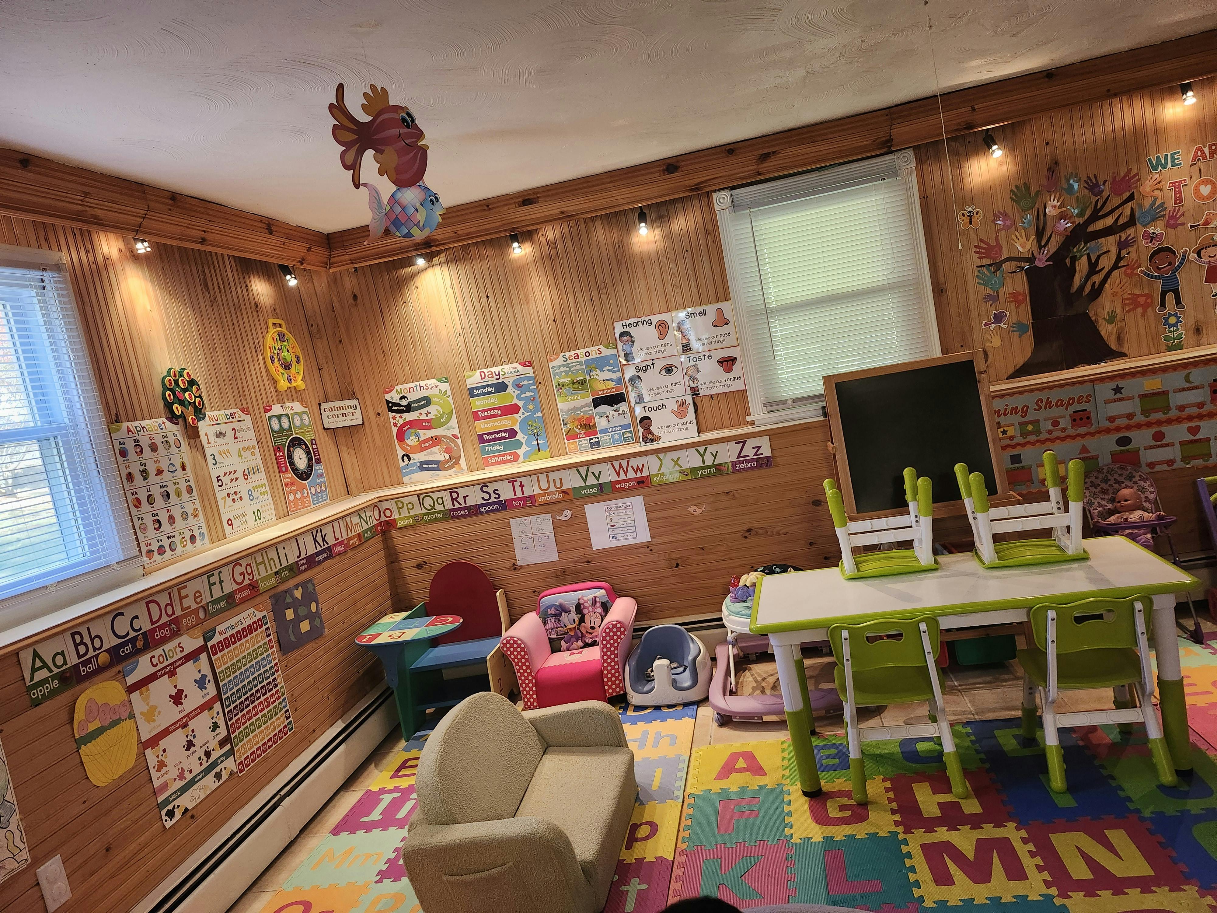 Children's playroom with small tables, chairs, and colorful alphabet floor mats