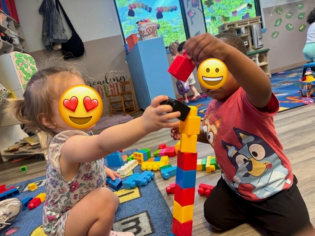 Two children stacking plastic building blocks in a classroom