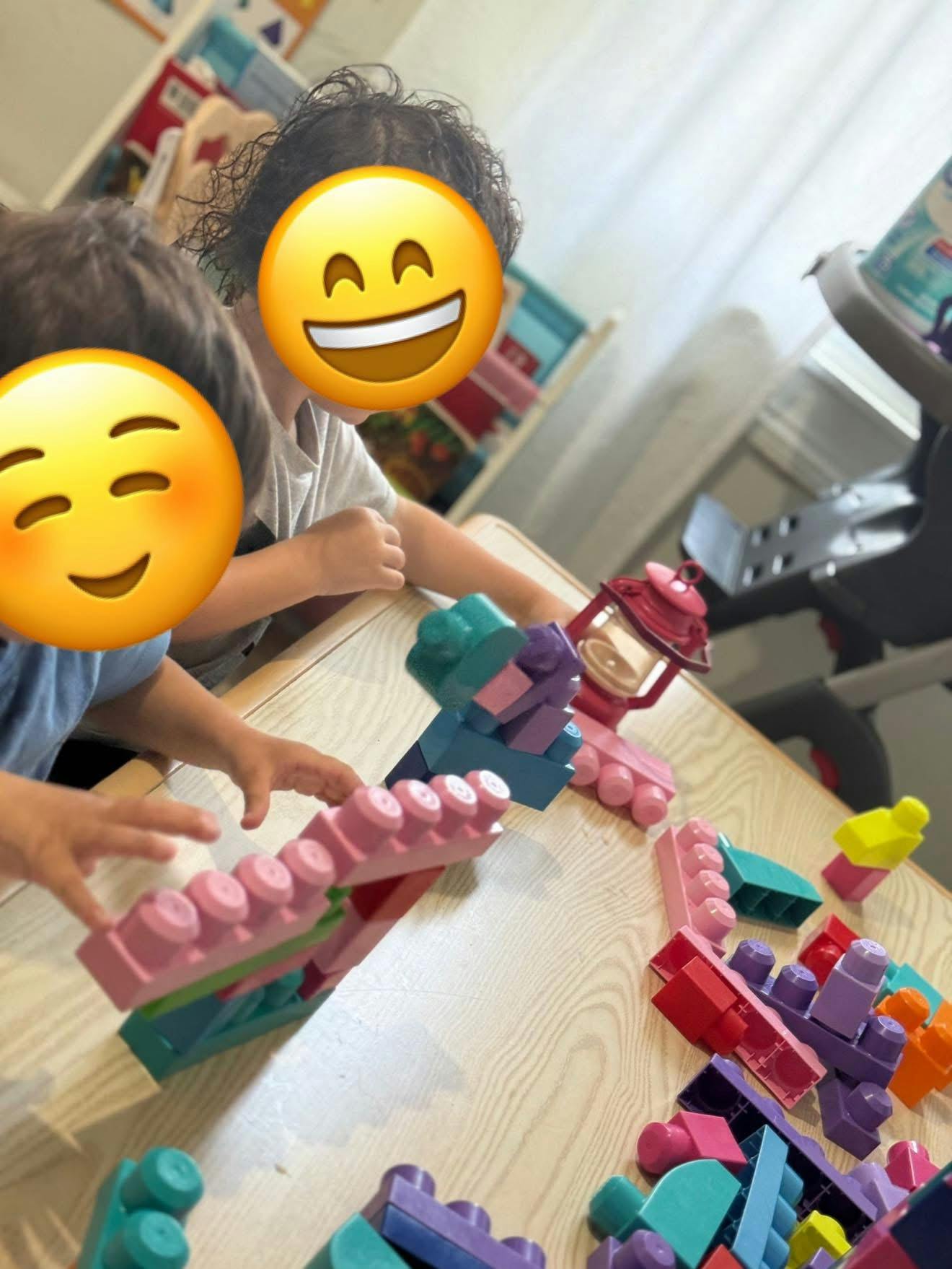 Two children playing with colorful building blocks at a table