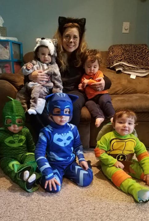 Person with cat ears holding two children, three other children in costumes