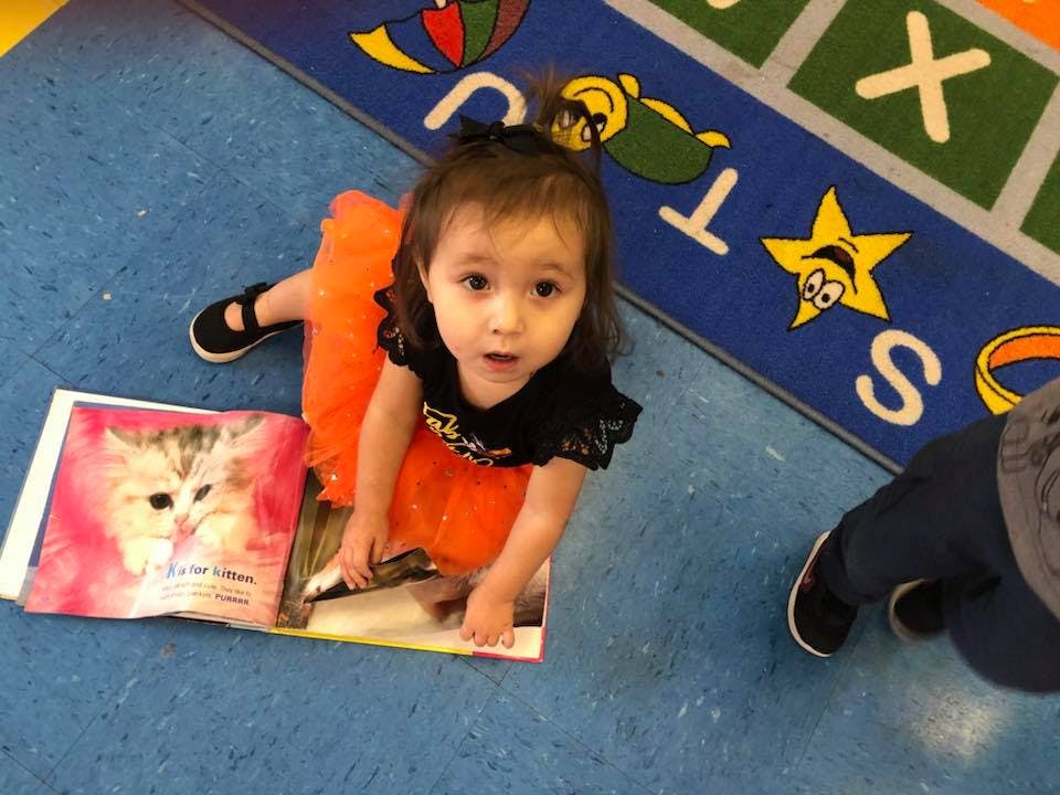 Child on floor looking up from open book